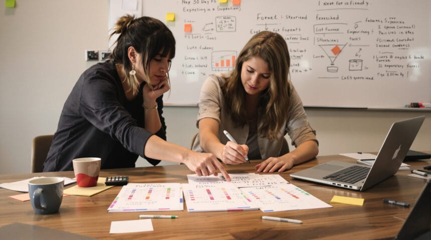 ROI-Driven Prospecting List Building Playbook for Small B2B Teams (with 3 Proven 30-Day Experiments) Small B2B team reviewing a blurred spreadsheet and three color-tabbed experiment card stacks at a wooden table.
